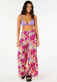 Lilla ribbet bikini top kombineret med bredbente bukser med pink, orange og lilla blomster mønstre. Materialet ser let og åndbart ud.
