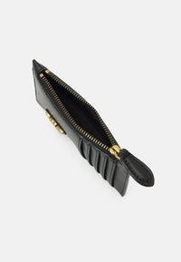 Schwarze Leder-Geldbörse mit strukturiertem Oberflächen, goldfarbener Reißverschluss und geriffelten Details an einer Seite. Offene Ansicht, die das Innenfach zeigt.