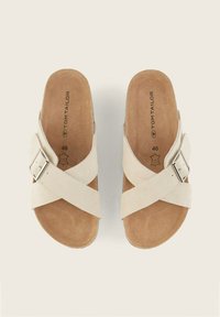 Beige mockaskinnsandaler med korsade remmar och en metallisk silverspänne. Mjuk, texturerad innersula med tryckt varumärke. Storlek 40.
