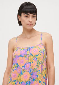 Floral dress in lightweight fabric featuring a pink, purple, and yellow flower pattern. Designed with thin straps and a relaxed fit.