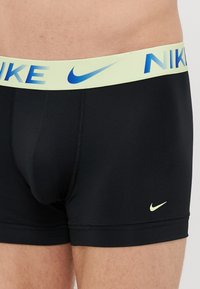Crne bokserice od rastezljivog materijala s svijetlozelenim pojasom na kojem je plavi natpis "NIKE" i malim bijelim logom na nozi.