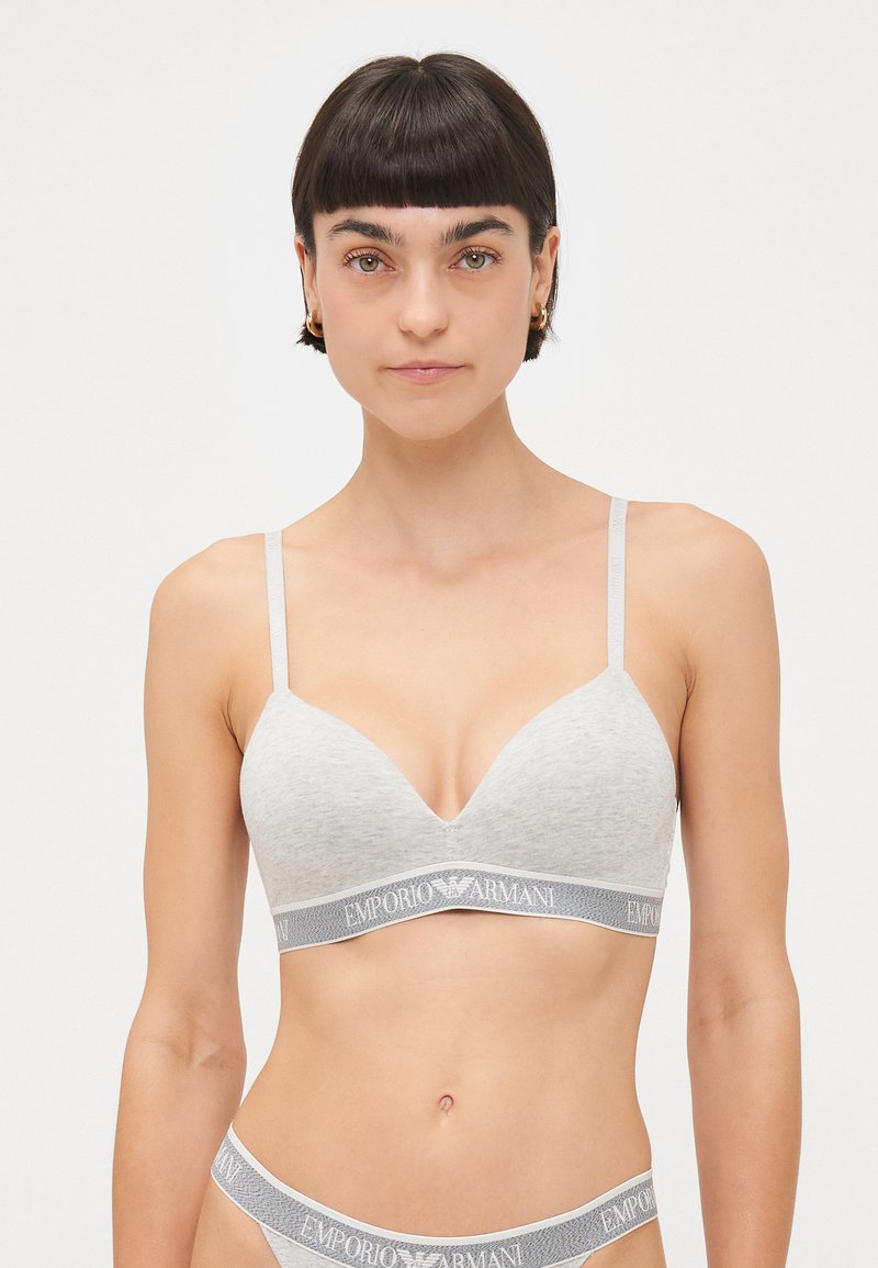 Light gray bra with a smooth texture, plunging neckline, thin straps, and an elastic waistband featuring the Emporio Armani logo.
