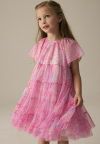 Rosa gestuftes Kleid mit fließenden Ärmeln, das ein marmoriertes Muster und subtile Funkeln über den Stoff aufweist. Das Material scheint leicht und durchscheinend zu sein.