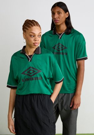 Grön kortärmad skjorta med svart krage och detaljer, som har ett geometriskt mönster och "UMBRO"-logotyp i svart fram.