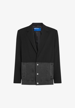 Juodas švarkas su pilku džinsiniu apatine dalimi. Turi apykaklę, priekinius mygtukus ir šonines kišenes. Viršutinė dalis lygi, apatinė dalis yra tekstūruota džinsinė.