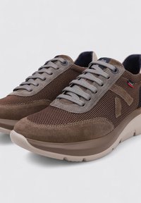 Zapatillas marrones que combinan materiales de malla y ante, con cordones grises y una suela de goma beige con detalles de acento a los lados.