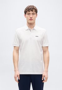 Λευκό πόλο μπλουζάκι με διακριτικό εξαγωνικό μοτίβο, με κούμπωμα δύο κουμπιών, κοντά μανίκια και το λογότυπο "BOSS" στο στήθος.