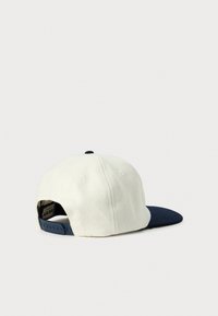 Hvid og marineblå snapback kasket med hvid krone og marineblå buet skygge vist fra bagsiden på en hvid baggrund.