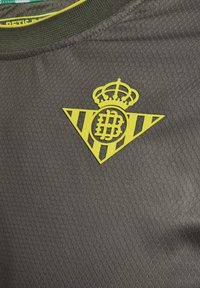 Svart atletisk tröja med en strukturerad tyg. Har ett gult emblem i triangulär form med ränder och en krona högst upp.