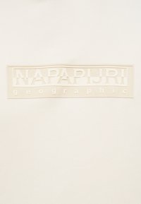 Μπεζ ύφασμα με ανάγλυφο ορθογώνιο λογότυπο που γράφει "NAPAPIJRI geographic" σε τόνους μπεζ που ταιριάζουν.