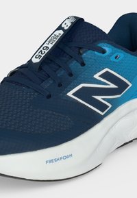 Μπλε και ναυτικό μπλε παπούτσι New Balance για τρέξιμο με λευκή σόλα, λογότυπο "N" και ετικέτα "Fresh Foam 625" στη γλώσσα και στη μέση της σόλας στο πλάι.