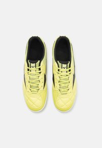Zapatillas deportivas amarillas con parte superior sintética acolchada, acentos negros y cordones trenzados. Cuenta con un collar acolchado y una construcción ligera.