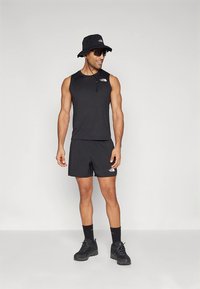 Juoda sportinė apranga, sudaryta iš berankovio viršaus ir šortų, papildyta kibiro formos kepure bei saulės akiniais, visa iš lengvos medžiagos.