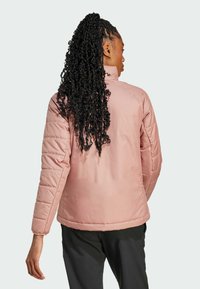 Veste rembourrée rose avec un col haut, des manches matelassées et une surface lisse. Présente une coupe décontractée et des poignets élastiques pour un confort supplémentaire.