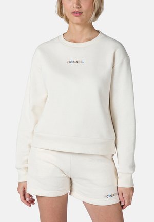 Conjunto de sudadera y pantalones cortos en color crema que presenta un cuello redondo, puños acanalados y el logotipo "ROSSIGNOL" bordado en letras iridiscentes.