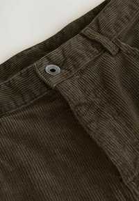 Donkergroene corduroy stof met verticale ribbels, voorzien van een knoopsluiting en lussen voor een riem in de taille. Gevarieerde en duurzame stof.