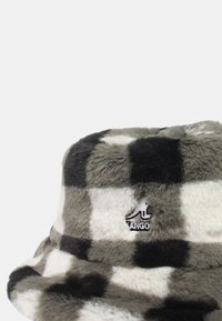 Chapeau seau à carreaux gris et blanc en fausse fourrure douce, avec un patch logo à l'avant et un large bord flexible.