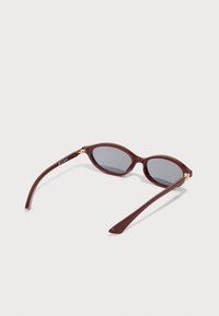 Burgundy plastic sunglasses with oval lenses, grey tinted, and slender arms featuring gold accents at the hinges.
