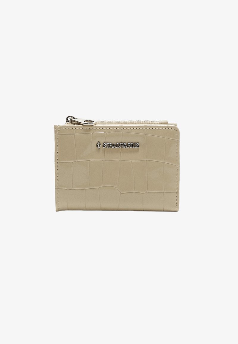 Beige leather wallet with a crocodile texture, featuring a zip closure and silver logo detailing on the front. Compact rectangular shape.