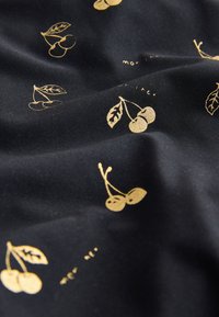 Črno blago z gladko teksturo, okrašeno z vzorcem zlatih češenj in drobnimi napisnimi poudarki. Češnje imajo liste in so različnih velikosti.