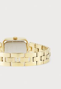 Gold-tone watch with a rectangular face, metal link bracelet, and textured links. Crown on the side, engraved accents on some links.