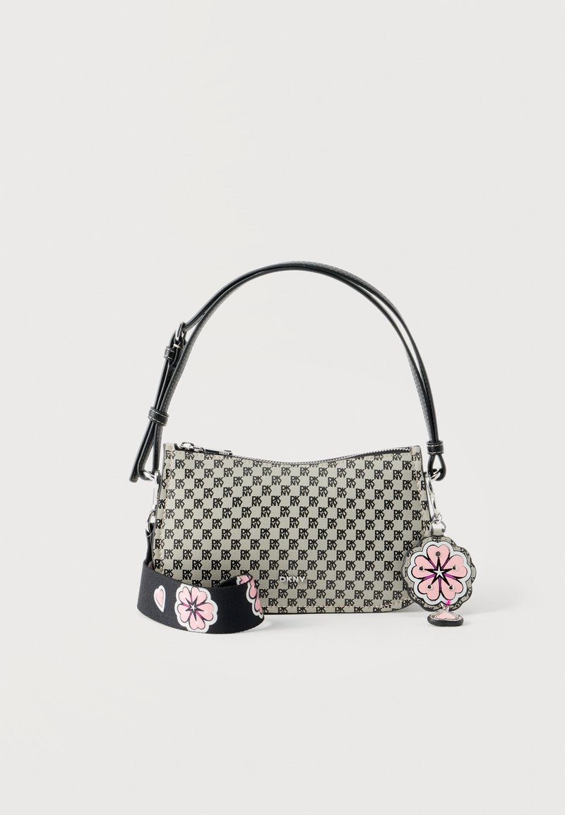 Μικρή ορθογώνια μπεζ τσάντα με επαναλαμβανόμενο μαύρο λογότυπο "DKNY", μαύρο χερούλι, αποσπώμενο μαύρο λουρί με ροζ σχέδια λουλουδιών και ροζ γούρι λουλούδι.