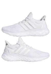 Paire de chaussures de running blanches Adidas avec tige en mesh respirant et semelle amortie, vue latérale montrant les trois bandes emblématiques.