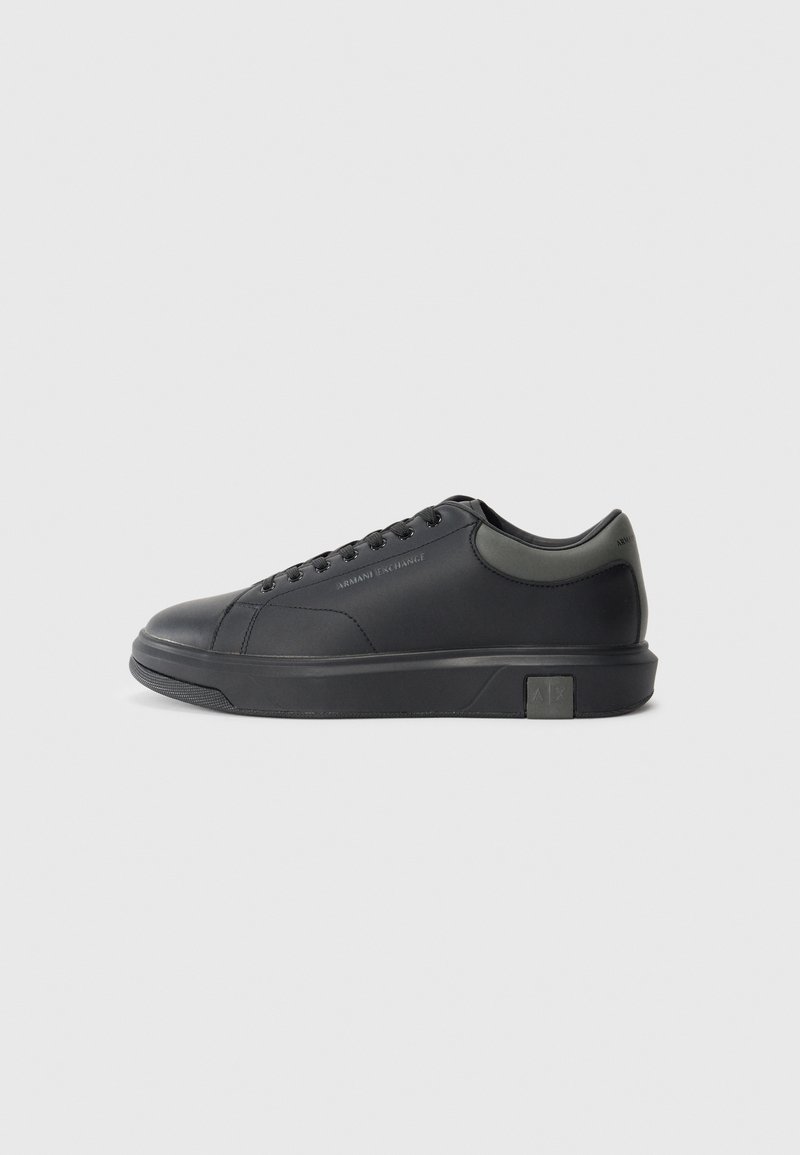 Sorte lærersneakers med en glat finish, rund tå og mørkegrå detaljer. Har snørebånd og en struktureret gummisål.