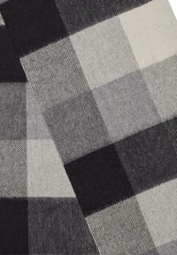 Czarna i szara tkanina w kratę z dużymi wzorami w kratkę, o miękkiej teksturze i mieszance ciemnych i jasnych tonów.