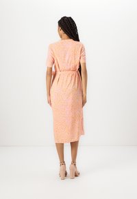 Pink and orange patterned dress with short sleeves, belted waist, and mid-calf length, paired with light-colored heeled sandals.
