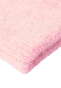 Roze, gestructureerde stof met een zachte, pluizige oppervlakte. Het materiaal lijkt dik en comfortabel, met een ribbelpatroon langs één rand.