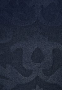 Mörkblått tyg med en subtil, texturerad mönstring med flytande former och kurvor, vilket skapar en mjuk, lager-på-lager visuell detalj.