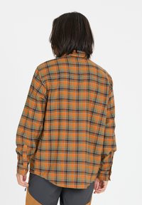 Oranssi, vihreä ja musta ruudullinen flanellipaita, jossa on napitettava kaulus, pitkät hihat ja hieman kaareva helma. Pehmeä rakenne, rento istuvuus.