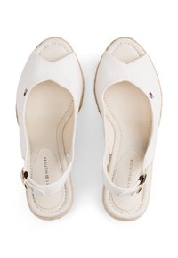 Ανοιχτά σανδάλια εσπαντρίγιες με εκρού ύφασμα και σόλα από γιούτα. Διαθέτουν λουρί πίσω με χρυσαφί μεταλλικά στοιχεία. Μινιμαλιστικές σχεδιαστικές λεπτομέρειες.