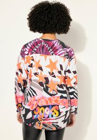 Langärmeliges Oberteil mit bunten geometrischen Mustern in Pink, Orange und Schwarz. Der Stoff hat eine glatte Textur und einen lässigen Schnitt.
