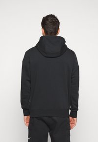 Felpa nera con cappuccio realizzata in materiale morbido, caratterizzata da una vestibilità comoda, maniche lunghe e una tasca a marsupio sul davanti.