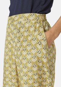 Pantaloni verdi a fantasia con motivi floreali bianchi e accentuazioni navy. Presentano un elastico in vita e tasche laterali per la praticità.