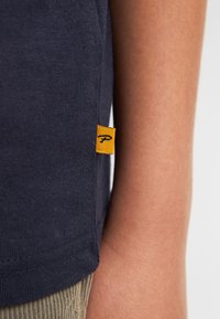 Marineblauw katoenen T-shirt met een gestructureerde afwerking, met een klein geel label met een zwart logo aan de zijnnaad.