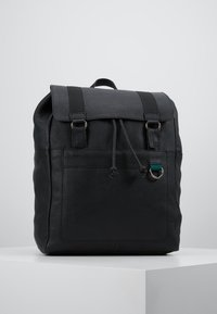 Svart läderryggsäck med en strukturerad yta, utrustad med ett topplock, två remmar och en framficka med dragsko.