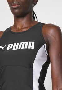 Czarny sportowy top na ramiączkach z białymi akcentami i wyraźnym logo PUMA, z okrągłym dekoltem i gładkim, elastycznym materiałem.