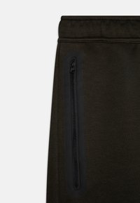Dark green sweatpants with a textured finish, featuring a black zippered pocket on the side and an elastic waistband for comfort.