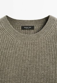 Grijze ribgebreide trui met een ronde halslijn. Kenmerkt zich door een label met "Massimo Dutti." Zachte textuur en een natuurlijke, gedempte kleurtint.