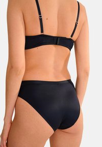 Ensemble de bikini noir avec un design épuré, des bretelles ajustables et une finition lisse. Le bas a une taille haute et des détails de couture minimaux.