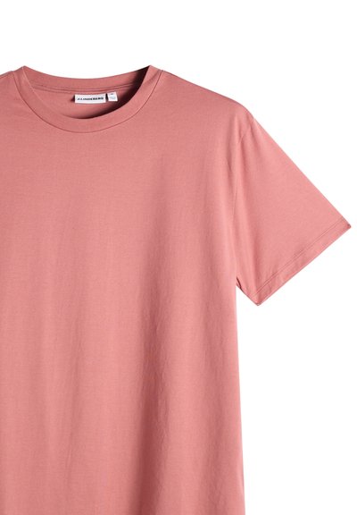 T-shirt en coton rose poussiéreux uni à manches courtes et col rond, avec étiquette de marque visible à l'intérieur du col sur fond blanc.