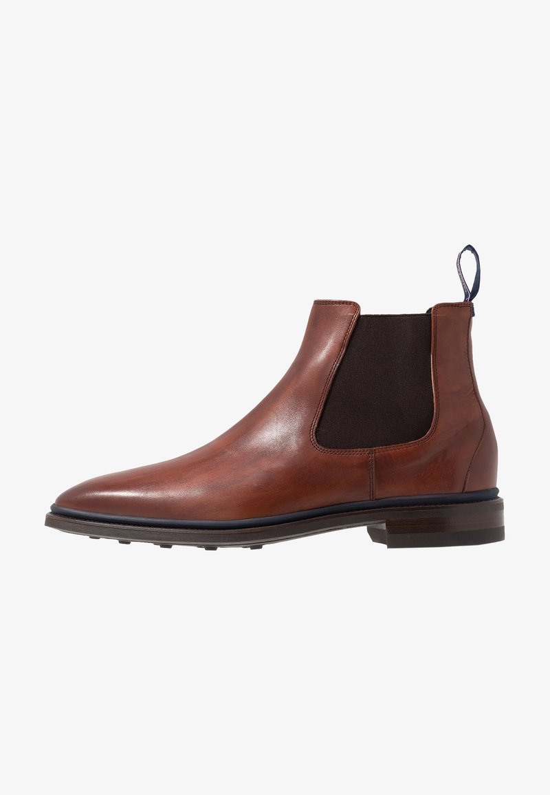 Bottes Chelsea en cuir marron avec des panneaux latéraux élastiques, un bout arrondi et une languette à tirer. La semelle est légèrement surélevée avec une finition texturée.