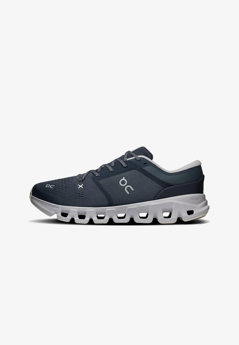 Baskets de sport bleu foncé avec semelle blanche épaisse comportant plusieurs découpes, logo blanc sur le côté et lacets bleu foncé.