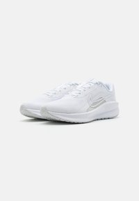 Pantofi sport albi cu un superior din plasă texturată, guler căptușit și swoosh argintiu reflective. Dispune de o talpă din cauciuc alb cu un model de prindere.