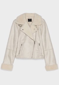 Kremowa kurtka z sztucznego baranka z kołnierzem z klapą, przednimi kieszeniami na zamek i mankietami na rękawach. Charakteryzuje się ukośnym zamkiem i miękką fakturą.