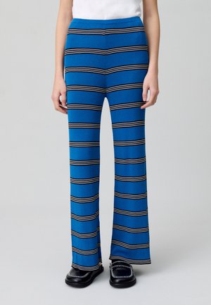 Pantalones de punto acanalado azul con rayas horizontales en blanco y negro, diseño acampanado, con una cinturilla ajustada y un corte relajado en las piernas.
