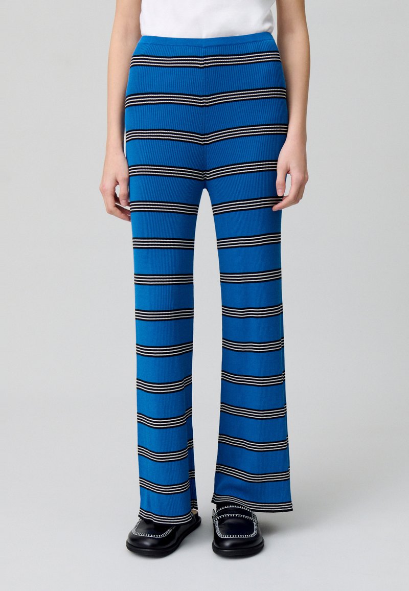 Pantaloni in maglia a coste blu con strisce orizzontali bianche e nere, design a zampa d'elefante, con una vita aderente e un fit rilassato lungo le gambe.